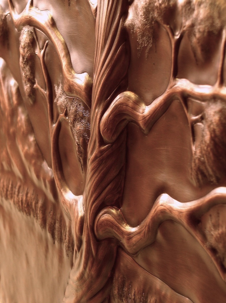 Dramatic repoussé of an aged juniper tree, set before mountains in the distance.